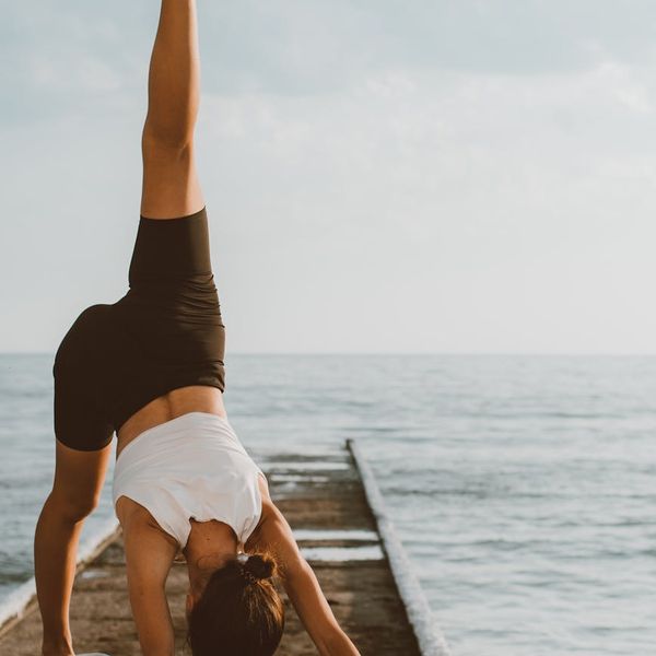 Child balancing on one leg in a tree yoga pose outdoors.